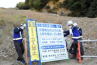１回目の行政代執行で盛り土の前に立ち入り禁止の看板などを立てる作業員＝北区有野町有野