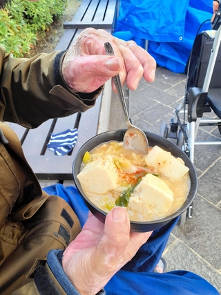 年末の炊き出しでマーボー丼を食べる男性＝２０２３年12月30日午後、神戸市中央区加納町６、東遊園地（撮影・高田康夫）
