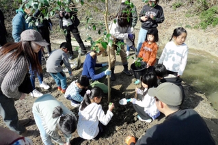 植樹に挑戦する親子ら＝神戸市須磨区（提供写真）
