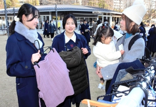 古着を求める来場者に説明する松蔭高校の生徒＝神戸市中央区加納町６、東遊園地
