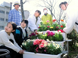 色とりどりの花が飾られたプランターを置く竜が台小学校の児童ら＝須磨区竜が台６