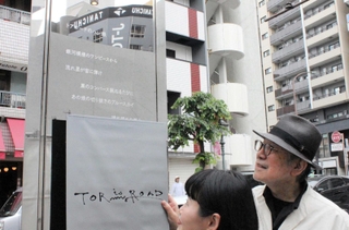 トアロードのアーチに刻字された新曲「トアロードのハレ娘」の歌詞を除幕する松本隆さん（右）＝神戸市中央区北長狭通