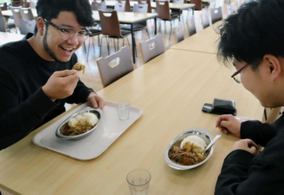 すき焼きのもとをアレンジしたカレーをほおばる学生＝神戸国際大
