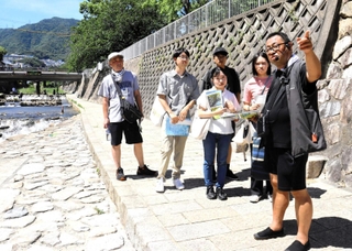 碓井さん（右）とともに都賀川水難事故の現場を訪れる参加者ら＝神戸市灘区内