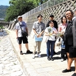 碓井さん（右）とともに都賀川水難事故の現場を訪れる参加者ら＝神戸市灘区内