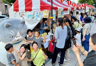 神戸新聞ブース前で「かなしきデブ猫ちゃん」のマルと記念撮影する来場者ら＝神戸市中央区東川崎町１（撮影・冨居雅人）