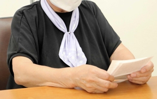 詐欺にあった日のことを書き記したメモを手に語る女性＝灘署
