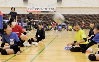 実業団バレーボールチームの選手と一緒にシッティングバレーを体験する子どもたち＝デンソーテン体育館
