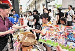 店主らと交流しながら商店街を巡る「まちあそび人生ゲーム」の参加者ら＝神戸元町商店街