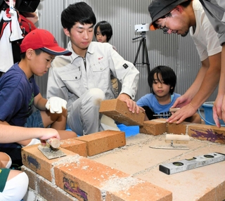 科学技術高校の生徒（中央）とかまどベンチ作りに挑戦した子どもたち＝灘区水道筋３