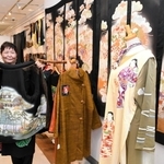 明治から昭和にかけての古布を加工した一点物の服が並ぶ会場と作者の岡宗さよみさん＝神戸市中央区明石町、大丸神戸店