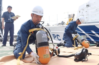 空気ボンベを装着する海上保安官ら＝神戸市中央区新港町