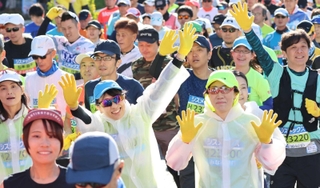 神戸マラソンのスタート地点で黄色い手袋を着け、両手を上げるランナーたち＝２０２３年１１月１９日、神戸市中央区