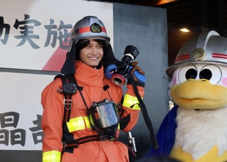 防火服を着たＡぇ！ｇｒｏｕｐの佐野晶哉さん（左）と市消防局のキャラクター「ウーカン」（右）＝兵庫区中之島２