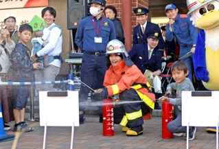 防火服を着用し、水消火器を体験する「Ａぇ！ｇｒｏｕｐ」の佐野晶哉さん＝兵庫区中之島２