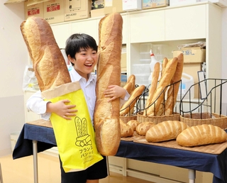 「意外と重い」と約１メートルの大きなフランスパンを抱える児童