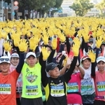 神戸マラソンのスタート地点で黄色い手袋を着け、両手を挙げるランナーたち＝２０２３年１１月１９日、神戸市中央区