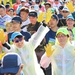 神戸マラソンのスタート地点で黄色い手袋を着け、両手を上げるランナーたち＝２０２３年１１月１９日、神戸市中央区
