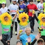 ヒマワリのかぶり物でそろってゴールするランナーたち＝２０２３年１１月１９日、神戸市中央区