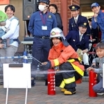防火服を着用し、水消火器を体験する「Ａぇ！ｇｒｏｕｐ」の佐野晶哉さん＝兵庫区中之島２
