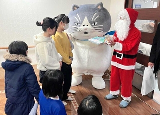 サンタクロース姿で「かなしきデブ猫ちゃん」の絵本をプレゼントする神戸イーストライオンズクラブの小林康弘会長（右）＝山手さくら苑