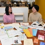 生活情報を多言語で翻訳した発行物などを前に、歩みを語る吉富志津代特別顧問（左）と李裕美理事長＝神戸市長田区海運町３