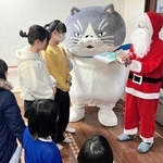サンタクロース姿で「かなしきデブ猫ちゃん」の絵本をプレゼントする神戸イーストライオンズクラブの小林康弘会長（右）＝山手さくら苑