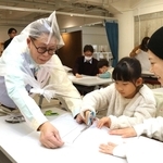 ごみ袋を使ったポンチョの工作に挑戦する親子と久保田雅人さん（手前左）＝神戸市中央区小野浜町