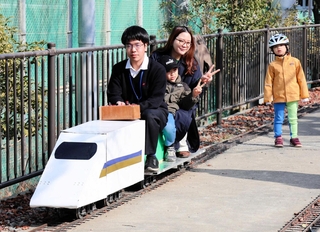 電気鉄道を操縦する市立科学技術高校の生徒と参加者ら＝神戸市中央区脇浜町１