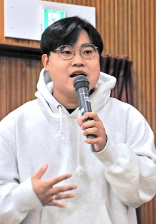 父の遺志を受け継ぎ、阪神・淡路大震災の記憶を継承するために運営を続けるカミングコウベについて紹介する上田佑吏さん＝須磨区宝田町２、滝川中学校