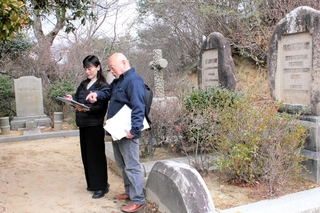 神戸市公園部森林整備事務所の榊原均さん（右）の案内で神戸市立外国人墓地を調べる長谷川純子さん＝同市北区山田町