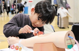 注射器を使って採血を体験する参加者＝神戸国際展示場