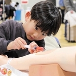 注射器を使って採血を体験する参加者＝神戸国際展示場