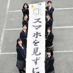 「スマホを見ずに安全確認」と呼びかける懸垂幕を制作した伊川谷北高と伊川谷高の生徒たち＝神戸西署