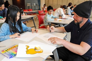 ワークショップで作った黄色いネコのオリジナルイラストを街中に貼る参加者＝中央区新港町