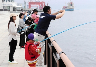 スタッフから助言をもらいながら、大物を狙う親子連れら＝マリンパーク