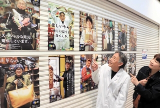 店主の個性あふれるポスターを眺める文勝弘さん（左）と立元香さん＝中央区北長狭通、ピアザ神戸