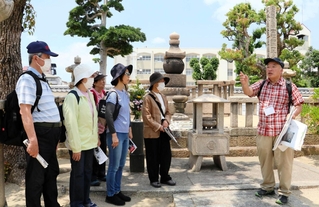 神戸空襲で大きな被害を受けた真光寺でボランティアガイドの説明を聞く参加者ら＝兵庫区松原通１
