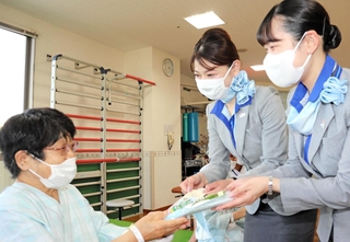 入院患者にスズランの花と手作りのしおりを手渡すＡＮＡの客室乗務員＝神戸赤十字病院
