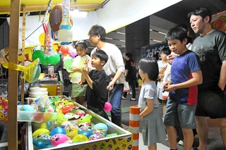 露店をのぞき、目を輝かせる子どもら＝阪神青木駅前