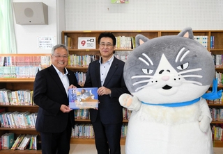中島竜也社長（中央）から絵本を受け取る赤木裕之校長＝神戸市灘区備後町1
