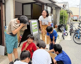 東京から新長田に移住し、開設予定のアトリエ前で子どもたちと話す織戸ゆみこさん＝神戸市長田区二葉町２