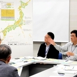 資源エネルギー庁や原子力発電環境整備機構の担当者（右奥）から説明を受ける参加者＝中央区港島中町６、神戸国際会議場