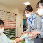 入院患者にスズランの花と手作りのしおりを手渡すＡＮＡの客室乗務員＝神戸赤十字病院