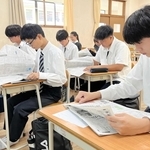 朝刊を開いて目を通す生徒＝啓明学院高校