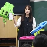 ライフジャケットを手に水難事故の恐ろしさを強調する岡真裕美さん＝西郷小学校