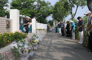 校門前に花を並べ、黙とうをささげる参加者ら＝神戸市西区美賀多台９