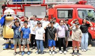 防災ジュニアチームのメンバーとなり、消防車の前でポーズをとる１３人＝本山第三小学校