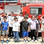 防災ジュニアチームのメンバーとなり、消防車の前でポーズをとる１３人＝本山第三小学校