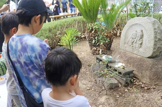 ２８年前の事件を胸に刻み、「なかよし地蔵」の前で手を合わせる子どもら＝神戸市須磨区友が丘８
